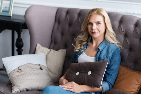 Pretty blond woman sitting on grey couch