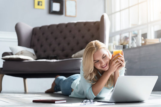 Blond woman lying on floor and holding juice glass