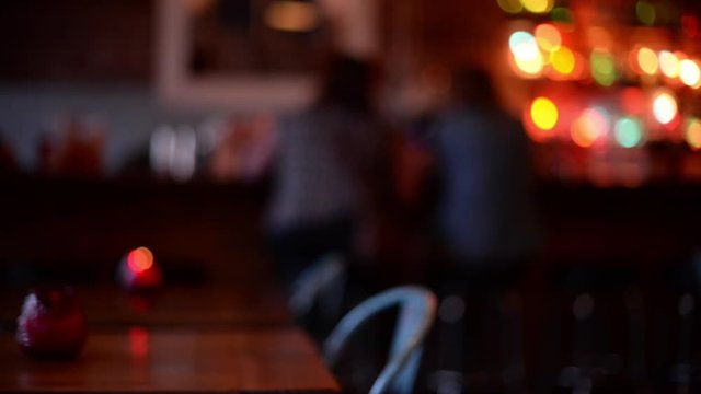 Blur shot couple at a bar, empty tables in.