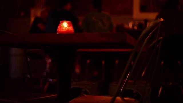 CU empty chair in bar, blur patrons in the background.