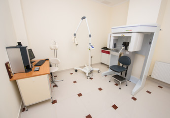 Dentistry clinic with modern orthopantomograph, dental panoramic x-ray machine to produce images in single shot entire dental system. Table with a computer which shows the x-ray photograph teeth