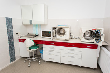 Sterilization room. Workplace in dentistry. Table with a packaging machine, ultraviolet shelf,...