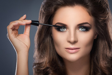 Fototapeta premium Beautiful woman applying mascara on her lashes