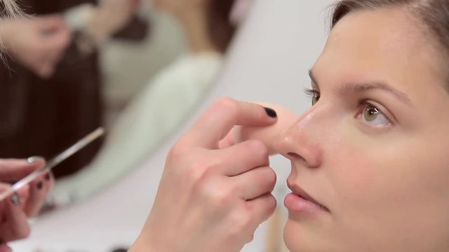 Make-up artist applies concealer on the model's face
