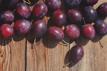 Fresh juicy plums in a wooden surface. Crop of plums