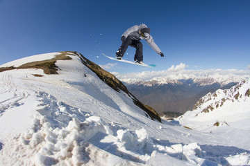 Naklejka na ściany i meble Snowboarder jumping in mountains, extreme sport.