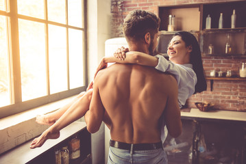 Sexy young couple in kitchen - obrazy, fototapety, plakaty