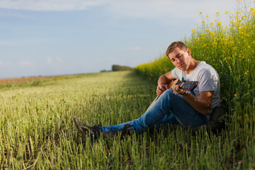 Naklejka na ściany i meble gay single man plays guitar in a field.