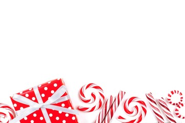 Christmas border of red and white gifts and peppermint candies over a white background