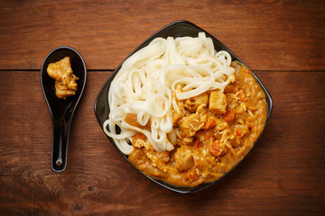 Curry sauce and noodles in blackplate at wooden table