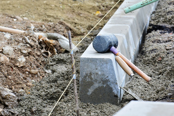 Concrete curb installation. String line level guide is stretched parallel to the line of course - obrazy, fototapety, plakaty