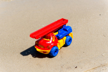 Toy truck with a boom in the wet sand. Summer holidays at sea. Special miniature.