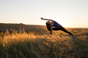 Woman doing yoga extended side angle pose during sunset