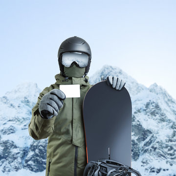 Young snowboarder holding blank lift pass with mountain on background