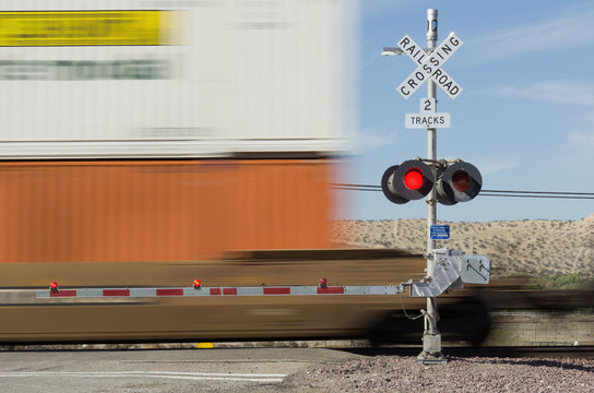 Railroad crossing sign and passing train. Photo taken in the Mojave desert near Victorville in California.