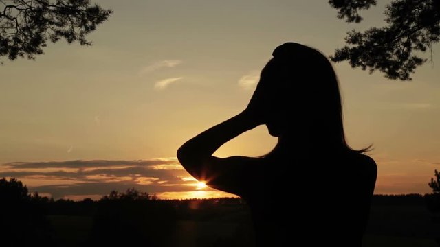 Woman putting on the headphones, listening to music and dancing in the forest. Sunset light, sun lens flares, golden hour. Relax, nature and joyful concept