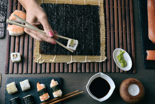 Woman preparing sushi rolls at home