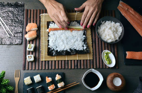 Woman preparing sushi rolls at home