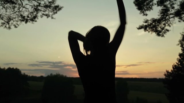 Young woman jumping and dancing in the forest after sunset. Freedom and happiness concept.