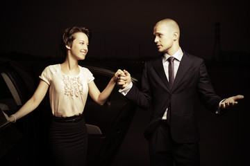 Young fashion couple next to car in the night