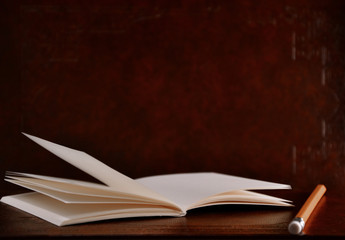 Open diary pocket book and pencil on brown vintage background