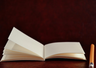 Open diary pocket book and pencil on brown vintage background