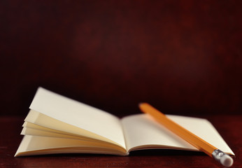 Open diary pocket book and pencil on brown vintage background