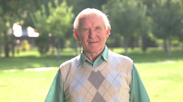 Senior man looks at camera. Male with gray hair outdoors. Remembering the past. Find purpose of life.