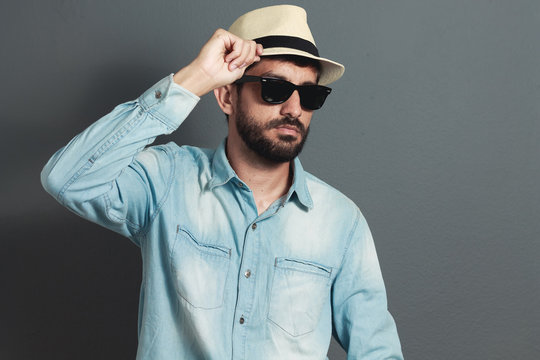 Young hipster bearded man wearing hat - gray background