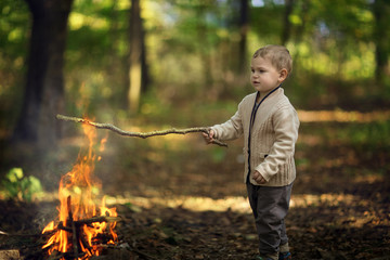 little boy playing with fire in the woods