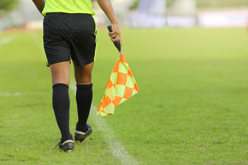 Assistant referees signalling with the flag on the sideline duri
