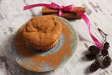 Muffins with plums and powdery cinnamon, cinnamon sticks on old wooden background, delicious dessert
