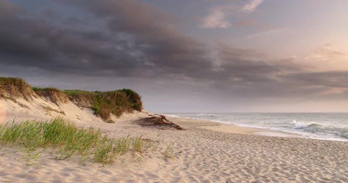 Wide shot of deserted beach and seashore with nice clouds and breakers rolling in on the sand