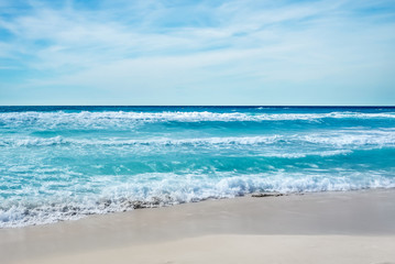 Fototapeta na wymiar Sandy beach backdrop with stormy water and blue cloudy sky