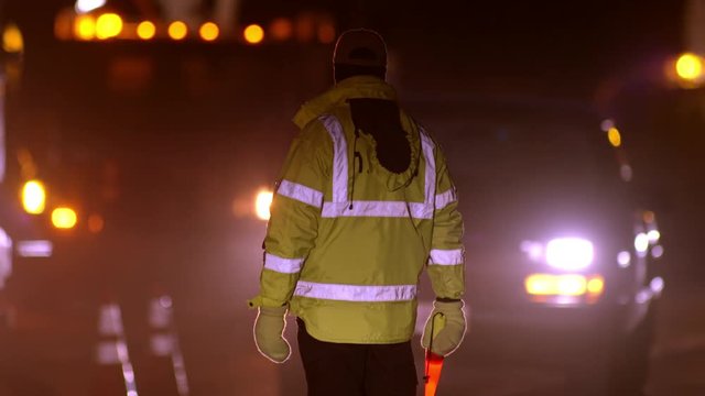 Rear View Of Police Officer Directing Traffic On The Street