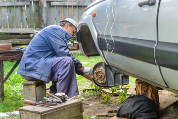 Senior mechanic replaces the vehicle's front wheel.