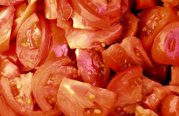 Cutting slices of red tomatoes, randomly scattered.