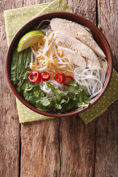 Vietnamese soup Pho Ga with chicken and rice noodles close-up. vertical top view