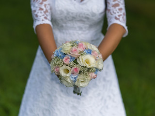 Beautiful tender wedding bouquet of cream roses and eustoma flowers in hands of the bride.