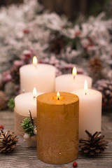 Fir branch in snow, lighted candle, cone on wooden background. Christmas theme