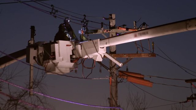 Utility workers in cherry picker working on powerline