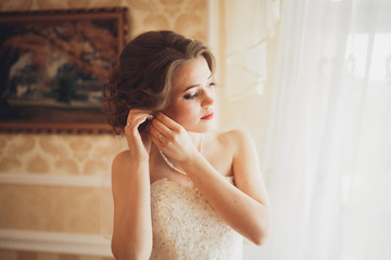 Naklejka premium Portrait of beautiful bride with fashion veil and dress at wedding morning