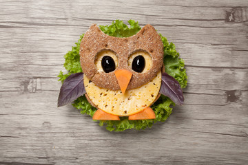 Owl made of bread and cheese on wooden background