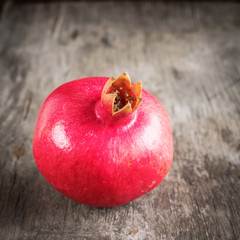 Big ripe pomegranate lies on an old wooden table.