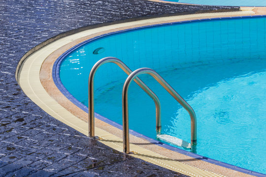The steel ladder and clear blue swimming pool.