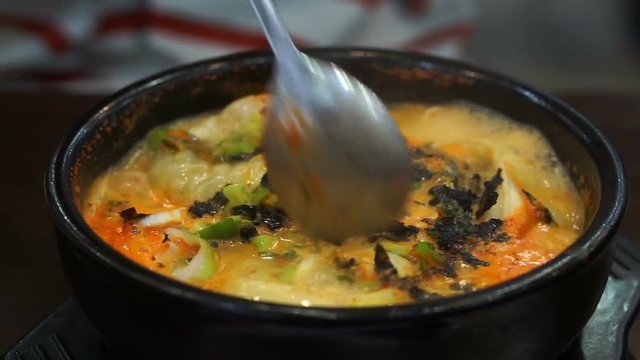 Spoon taking dumpling from Korean spicy stew serve in hot pot