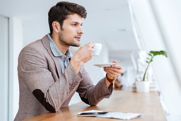 Casual young businessman drinking coffe while sitting in cafe