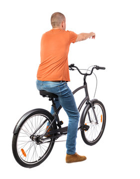 back view of pointing man with a bicycle. cyclist sits on the bike.  Rear view people collection.  backside view of person. Isolated over white background.
