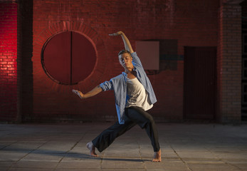 Young man in a dance pose on urban background.