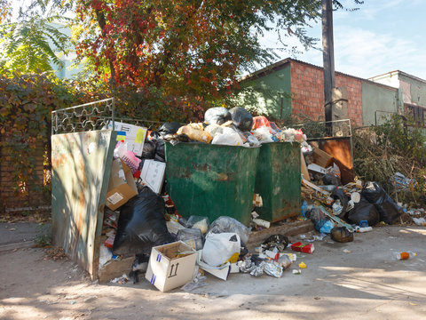 Dumpsters being full with garbage on the street of city